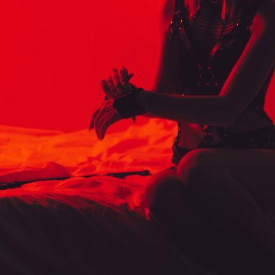 submissive sexy woman in underwear sitting on the bed puts handcuffs on her hands in the bedroom. BDSM concept of sex